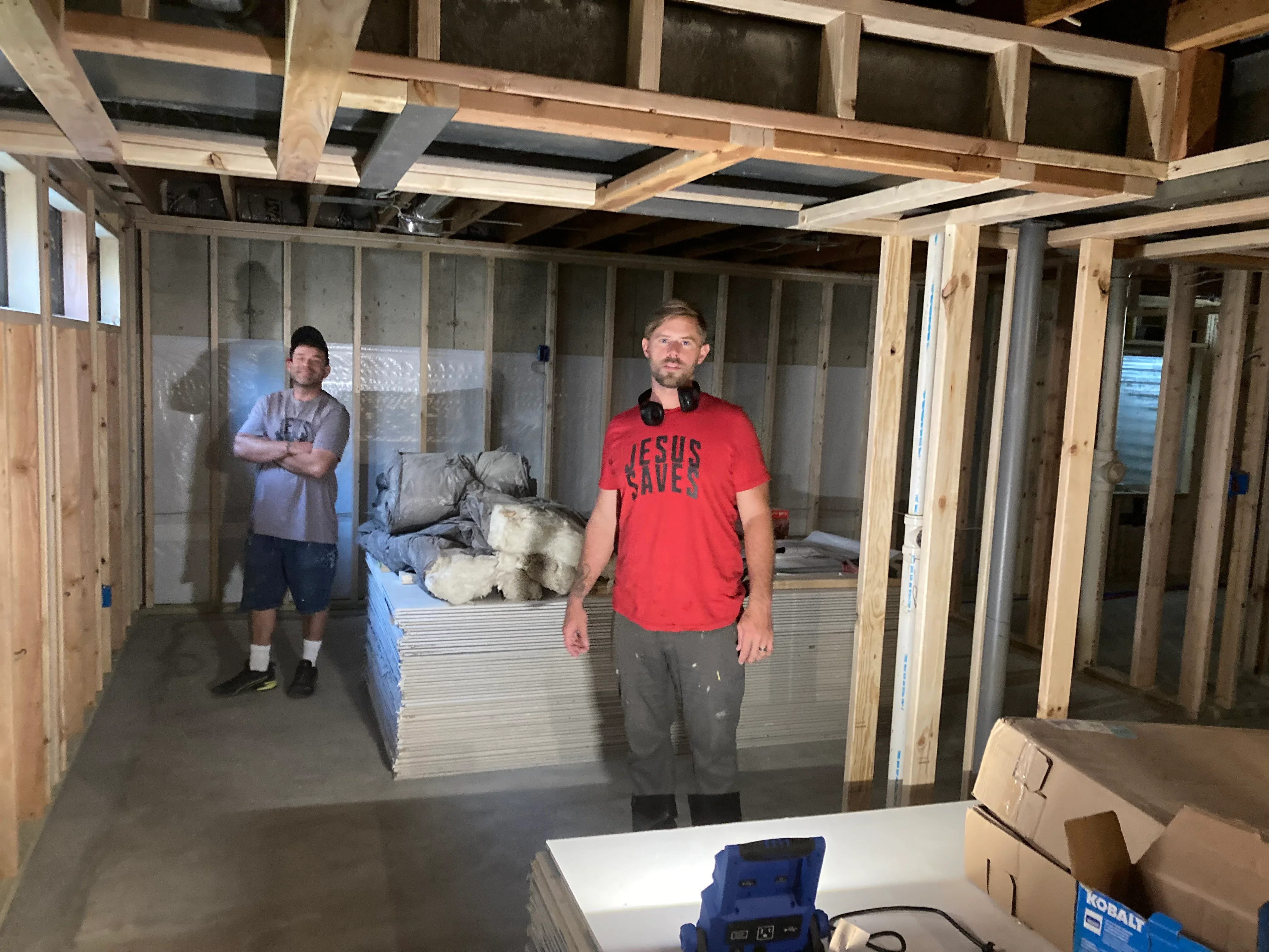 Basement framing with wooden studs, drywall panels, and insulation batts during construction